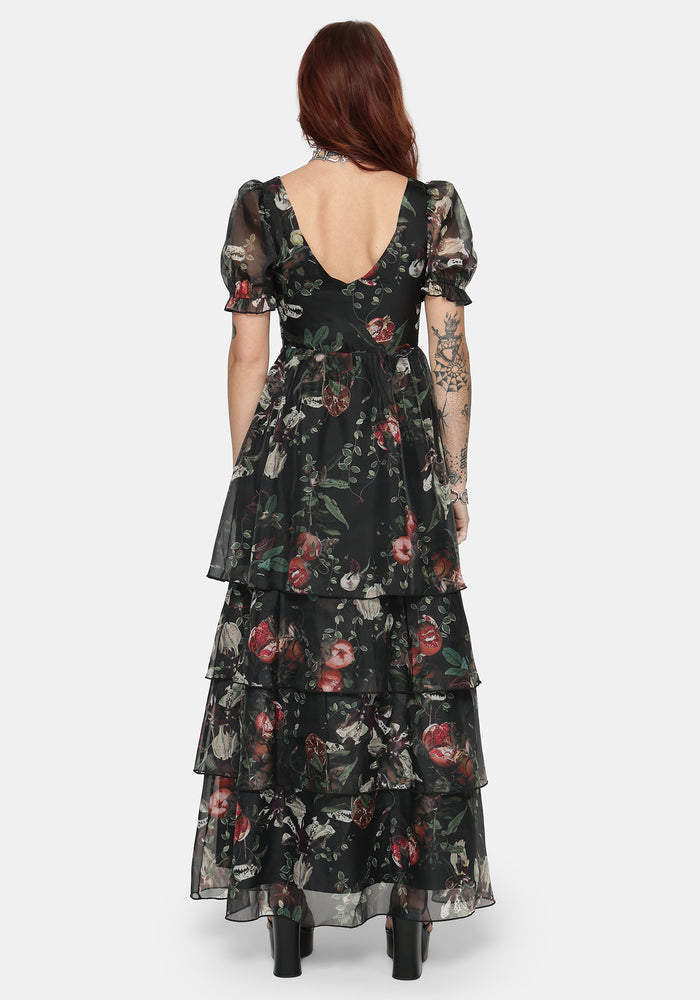 Woman wearing a fruit printed ruffle maxi dress with a white background