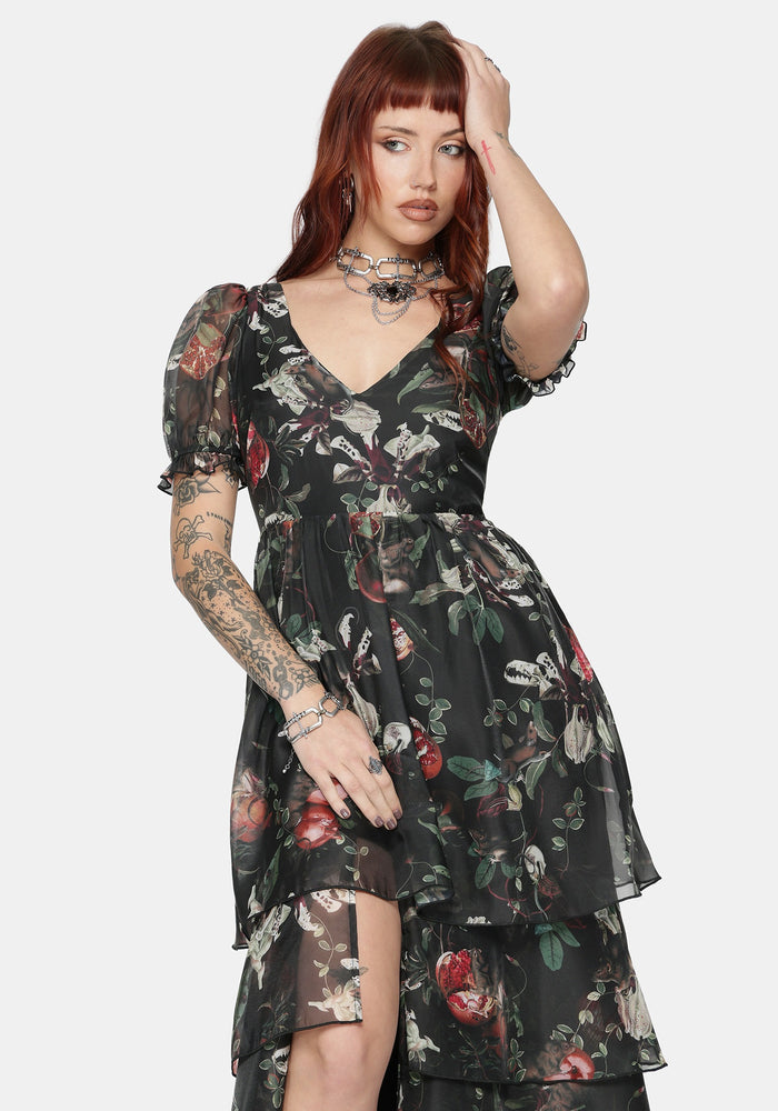 Woman wearing a fruit printed black maxi dress with a white background