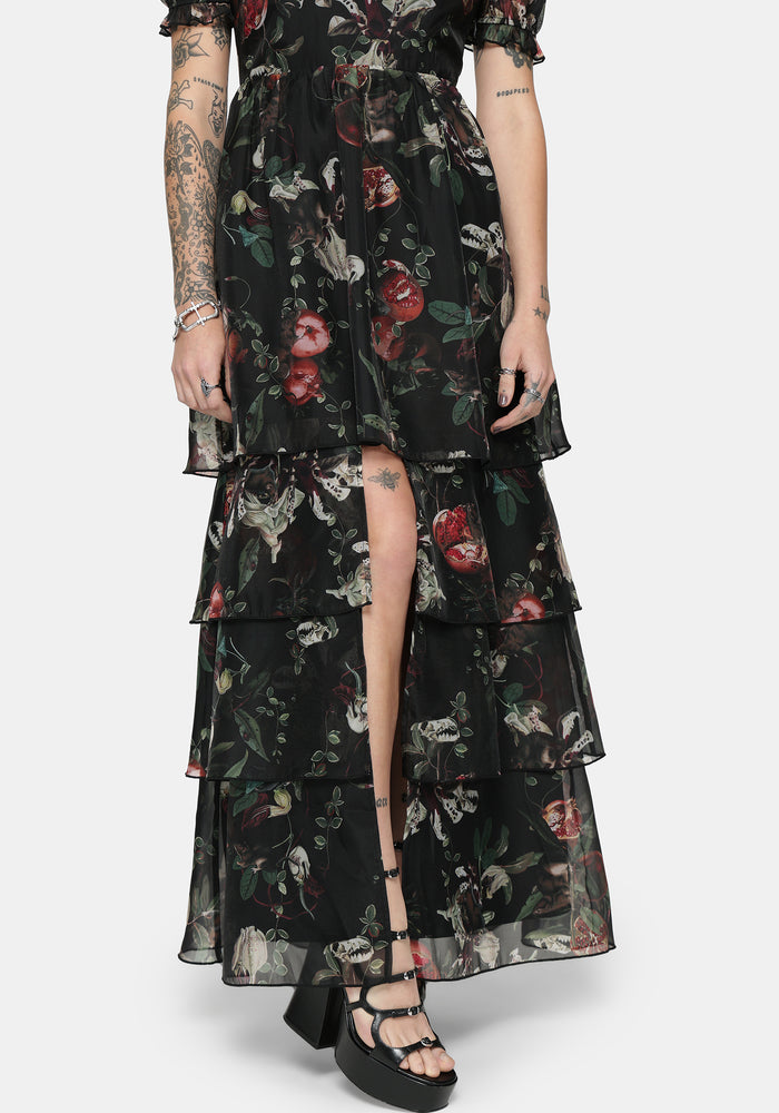 Woman wearing a black fruit printed maxi dress with tiered layers on a white background