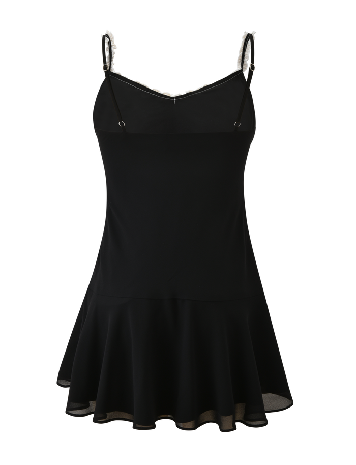 The ARIANNE MINI DRESS by TIGERMIST is a black mini dress with thin spaghetti straps, a fitted bodice, flared ruffled hem, and features subtle white lace trim on the straps and delicate ruffle trim along the hem.