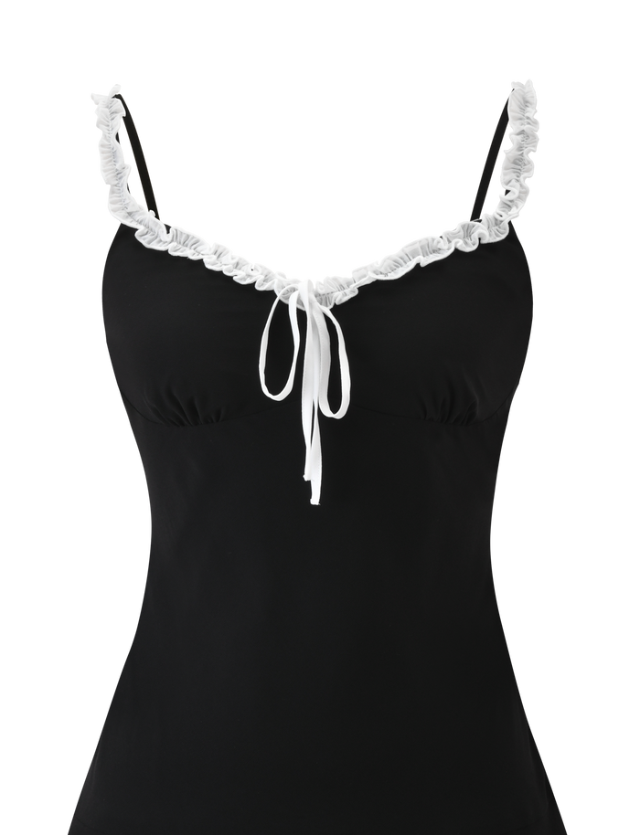 The ARIANNE MINI DRESS by TIGERMIST is a black mini dress featuring thin straps, ruffle trim on the sweetheart neckline, and a white tie bow at the center front.