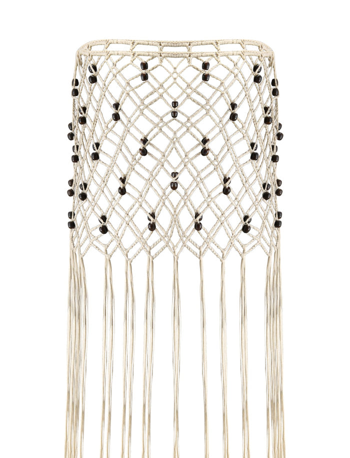 Introducing the ARLO CROCHET COVER-UP - CREAM by TIGERMIST: a decorative crochet piece featuring a diamond pattern accented with interwoven black beads. Long, fringed cords elegantly cascade from the hem, reminiscent of a fringe skirt, all crafted from cream-colored material.