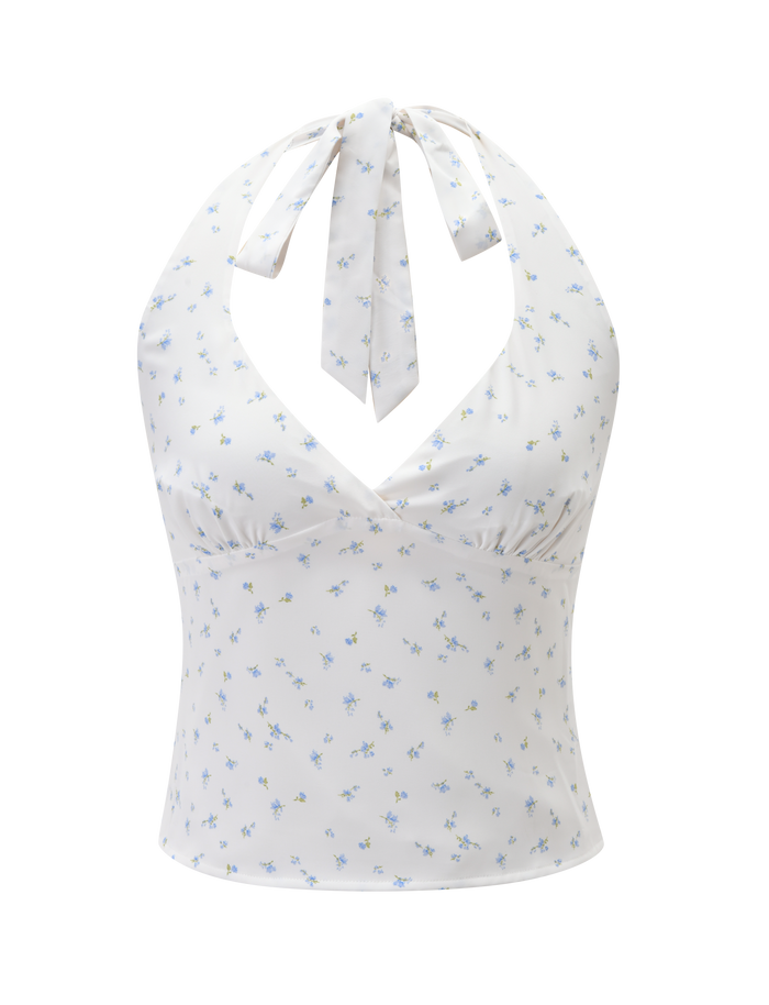 The CALI TOP - DITSY FLORAL by TIGERMIST is a white fitted, sleeveless halter neck top with a tie at the neck, featuring a blue ditsy floral print, light yellow accents, and ruched bust detail.