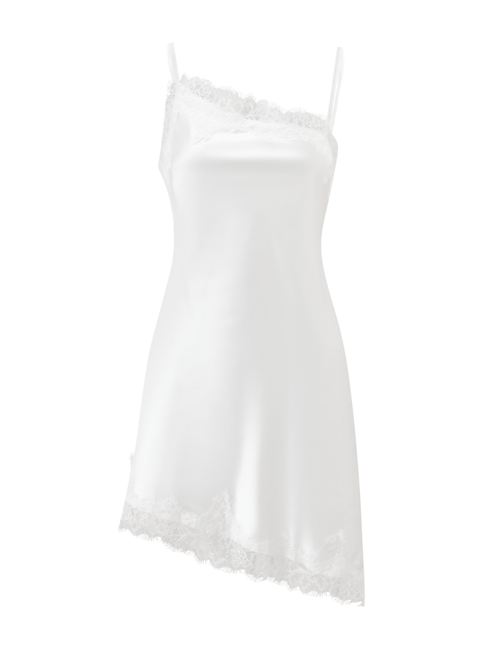 The ILARIA MINI DRESS - IVORY by TIGERMIST is a white satin mini dress with an asymmetrical hem, thin straps, and scalloped lace trim, showcasing a smooth, elegant look against a plain white background.