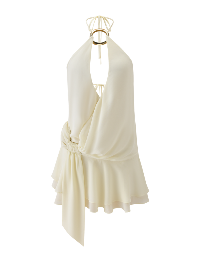 The INDIGO MINI DRESS 2.0 by TIGERMIST is a sleeveless ivory halter mini with a deep V-neckline, gathered adjustable waist, draped fabric, ruffle hem, ring detail at the neckline, and tie-back straps for a customizable fit.