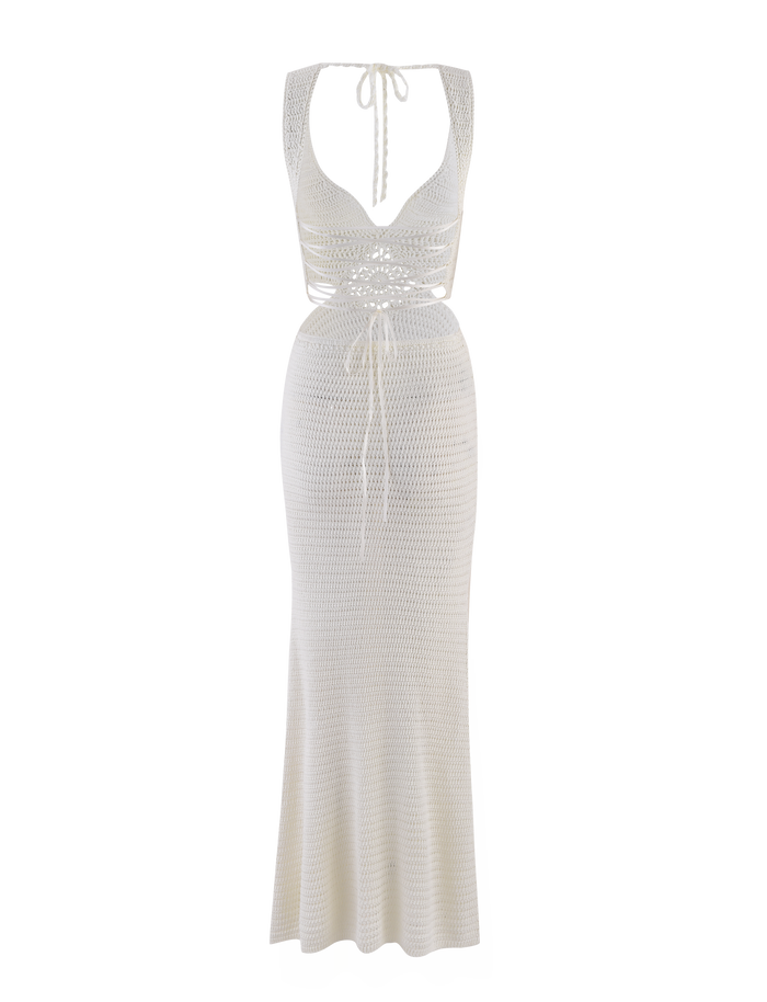 The TIGERMIST JONAH MAXI DRESS in cream is a long, white crochet dress with a deep v-neck, halter straps, front crisscross ties, a figure-hugging fit at the waist and hips, and a slightly flared hem for graceful movement.