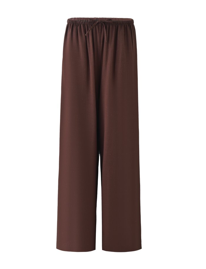 The TIGERMIST LAINEY PANT - CHOCOLATE features a loose fit, wide legs, mid-rise elastic waist, and functional side seam pockets, shown against a plain background.
