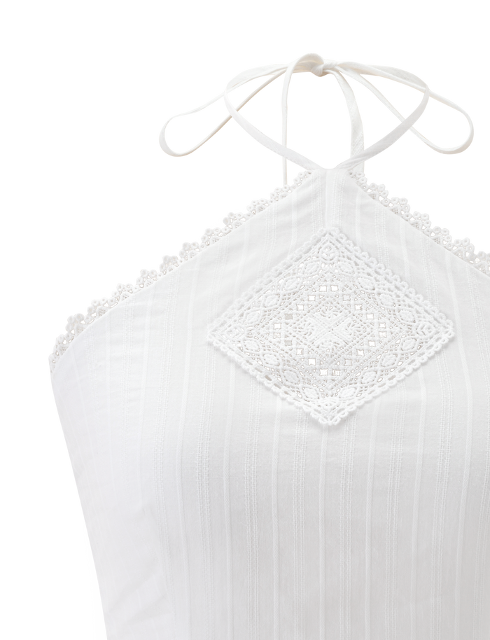 A close-up of the TIGERMIST LILETH TOP in white, showcasing a halter neck with a lace diamond pattern center and scallop eyelet trims on the neckline. The textured woven fabric has subtle vertical stripes.