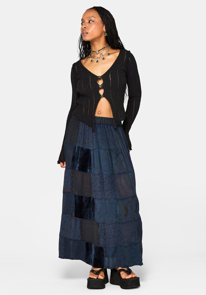 Woman wearing a black cardigan and layered navy skirt on a white background