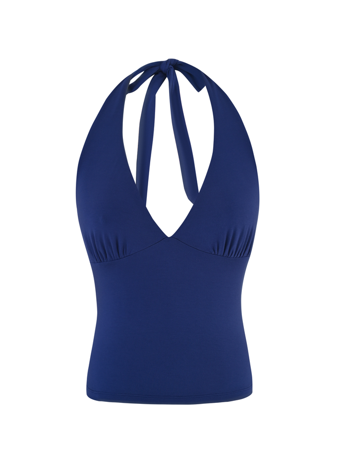 The MERIAL TOP by TIGERMIST is a sleeveless, denim blue halter with a V-neckline, tie-back neck, fitted waist, and made from smooth, stretchy jersey fabric.