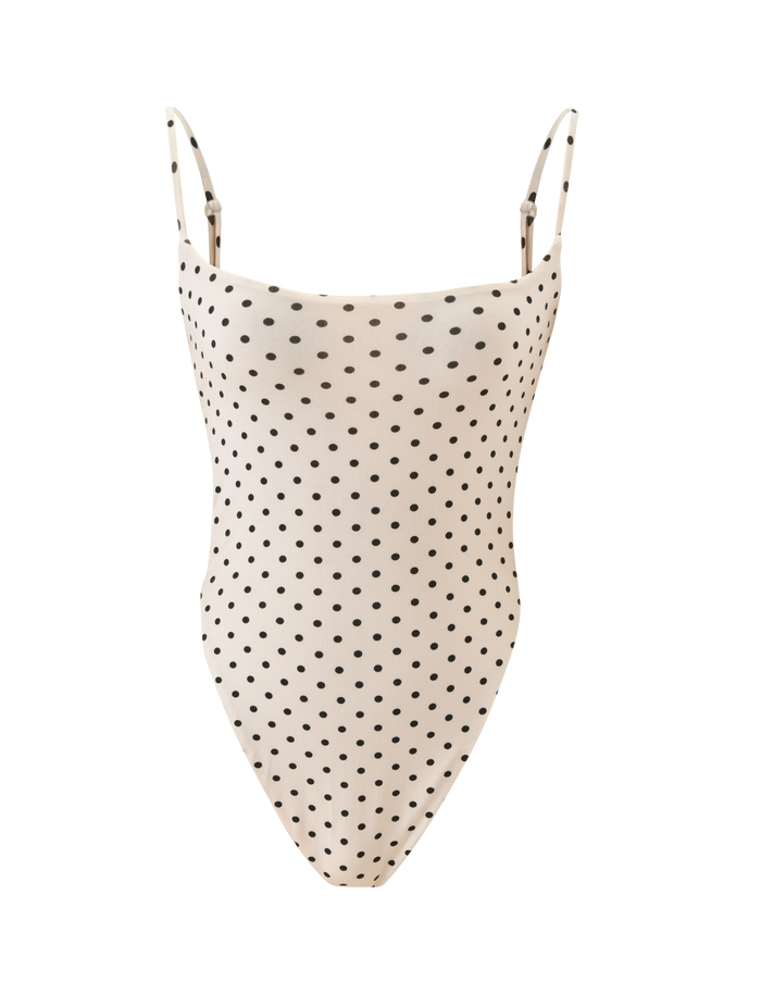 The MINERVA BODYSUIT - CREAM DOT by TIGERMIST is a white one-piece with thin shoulder straps, black polka dots, and a bodycon fit, shown against a plain white background.