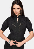 Woman wearing a black blouse with floral cut out details on a white background