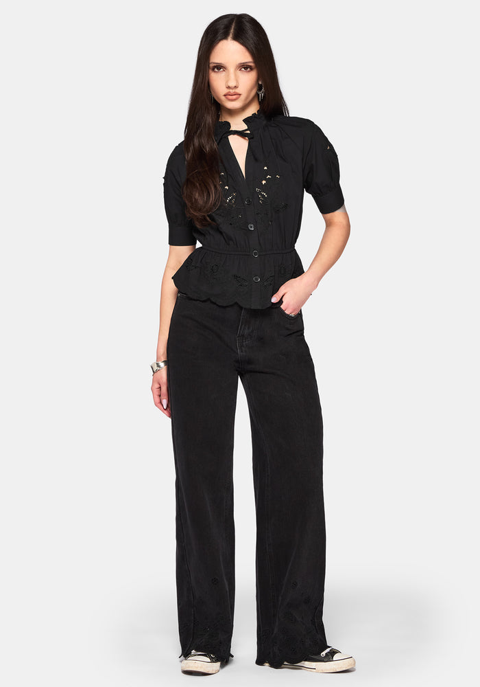 Woman wearing a casual black outfit with a peplum top and wide-leg trousers on a white background