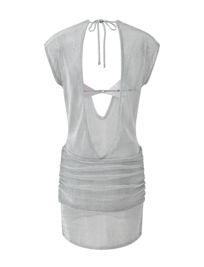 The ZOSIA MINI DRESS by TIGERMIST is a sheer silver knit mini dress with cap sleeves, an open back with neck tie, draped and twisted drop waist, and a scooped back cutout featuring a visible strap across the upper back.